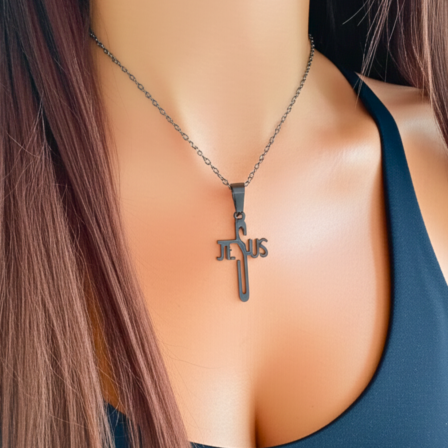 Necklace with 'Jesus' pendant on a person wearing a blue top