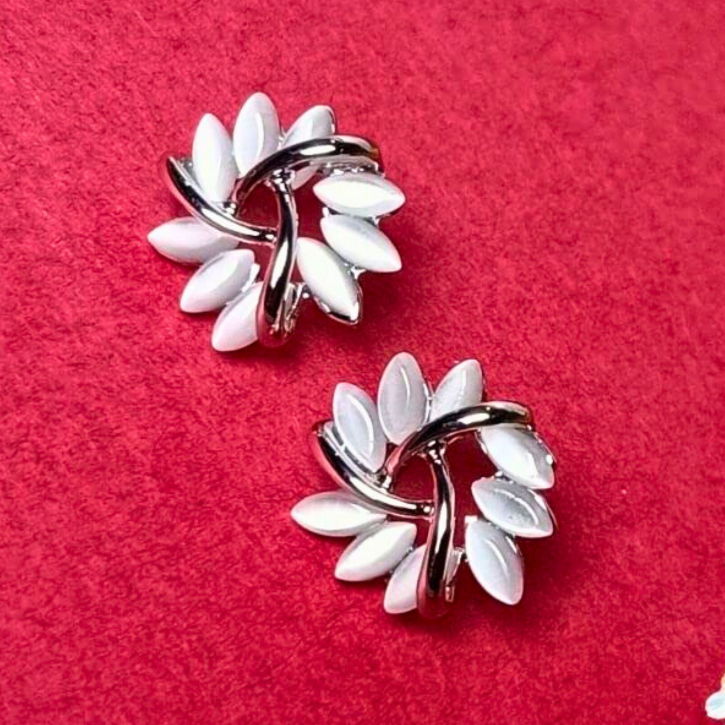 Pair of earrings with white floral designs on a red background