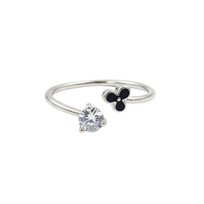 Silver ring with a heart-shaped gemstone and clover charm on a white background