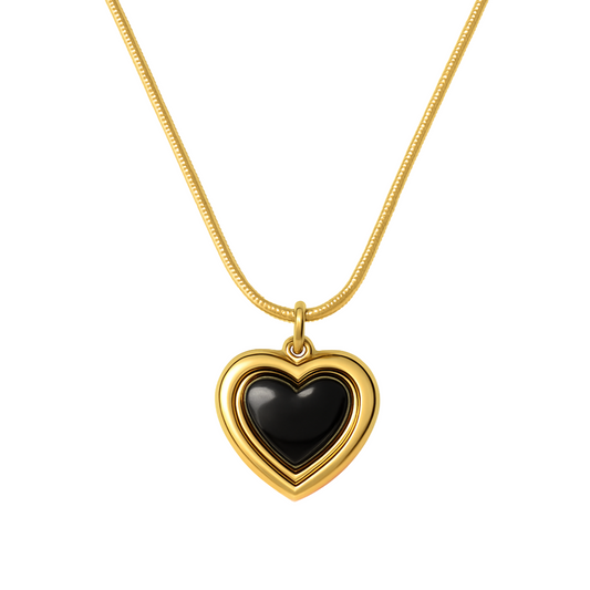 Gold necklace with a heart-shaped pendant featuring a black center on a white background