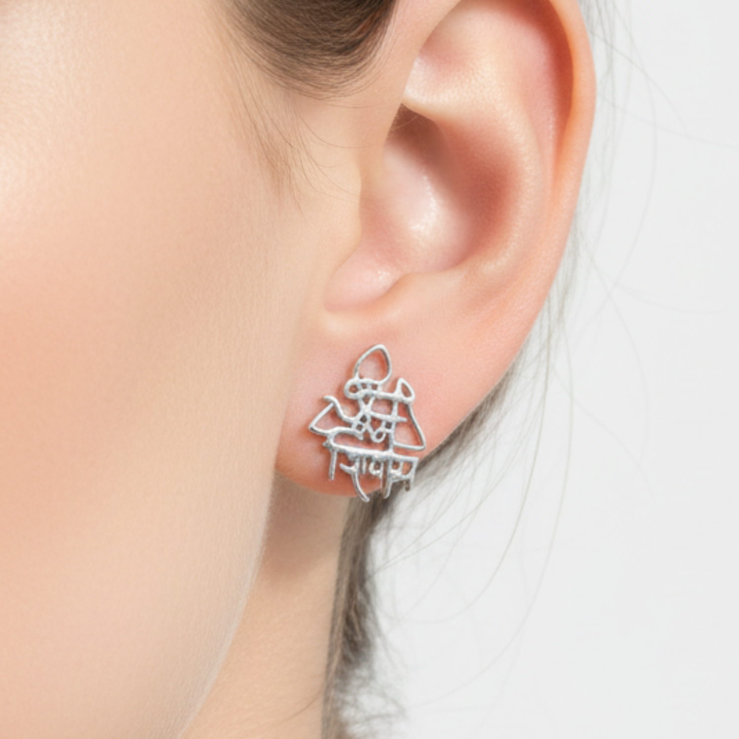 Silver earrings worn by a person with a blurred background