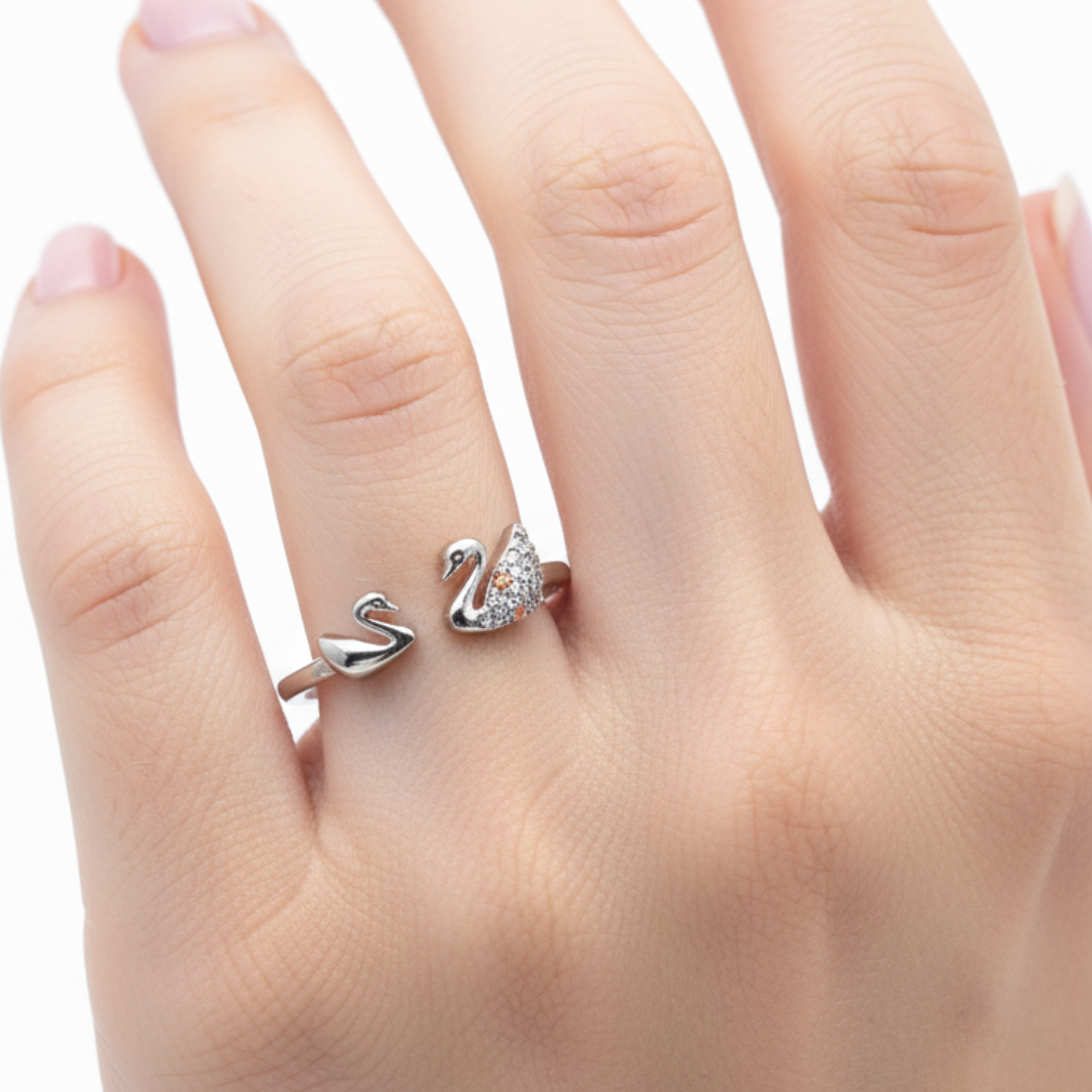 Two swan-shaped rings on a hand against a white background
