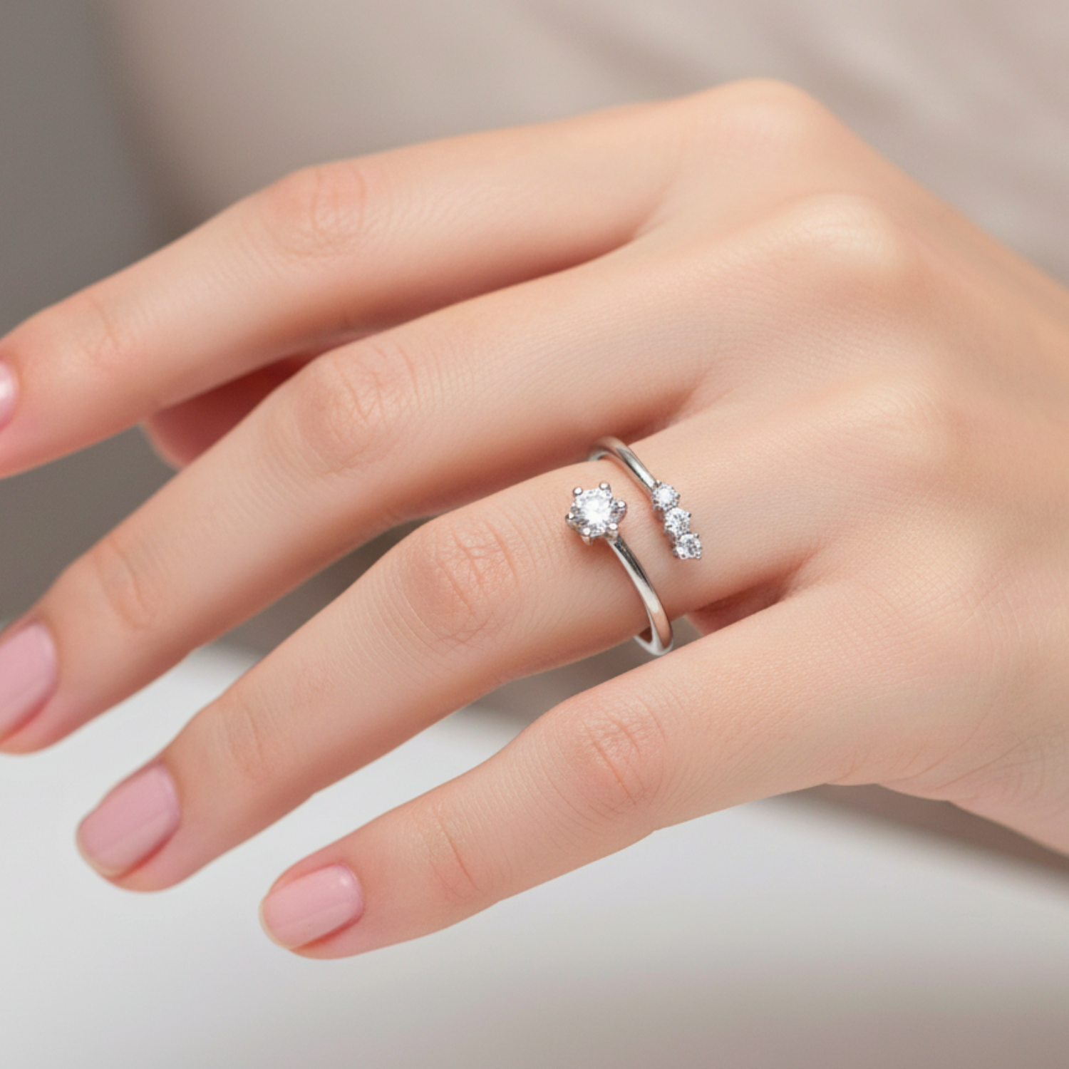 Hand wearing a silver ring with a diamond on a neutral background