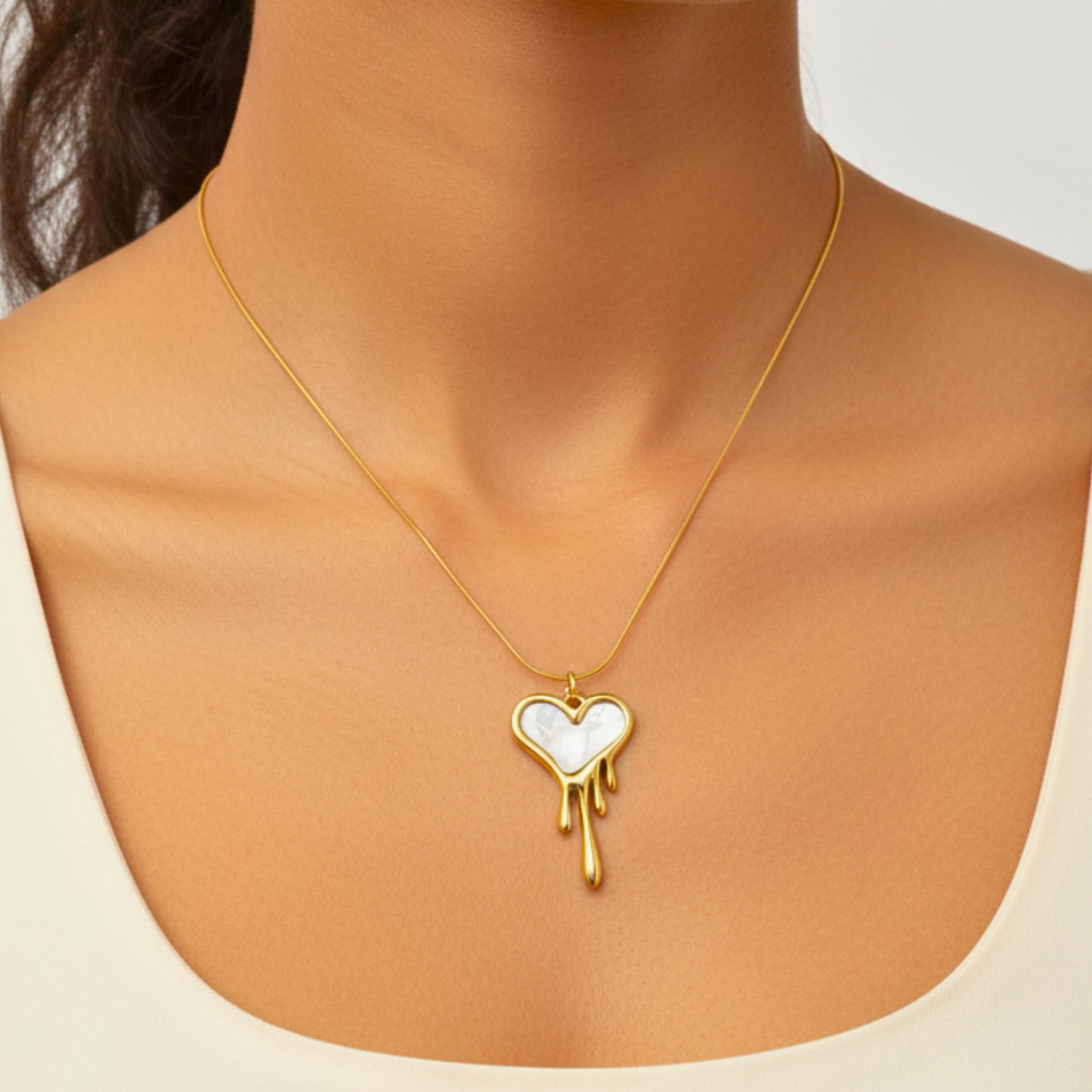 Gold necklace with a heart-shaped pendant on a neutral background