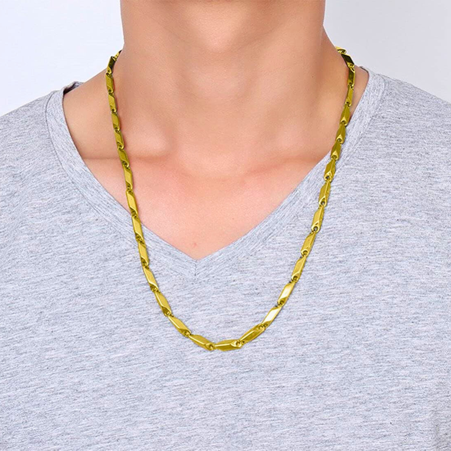 Gold chain necklace worn by a person on a plain background