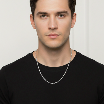 Man wearing a silver chain necklace against a plain background