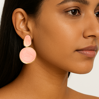 Close-up of a woman wearing pink circular earrings with gold accents.