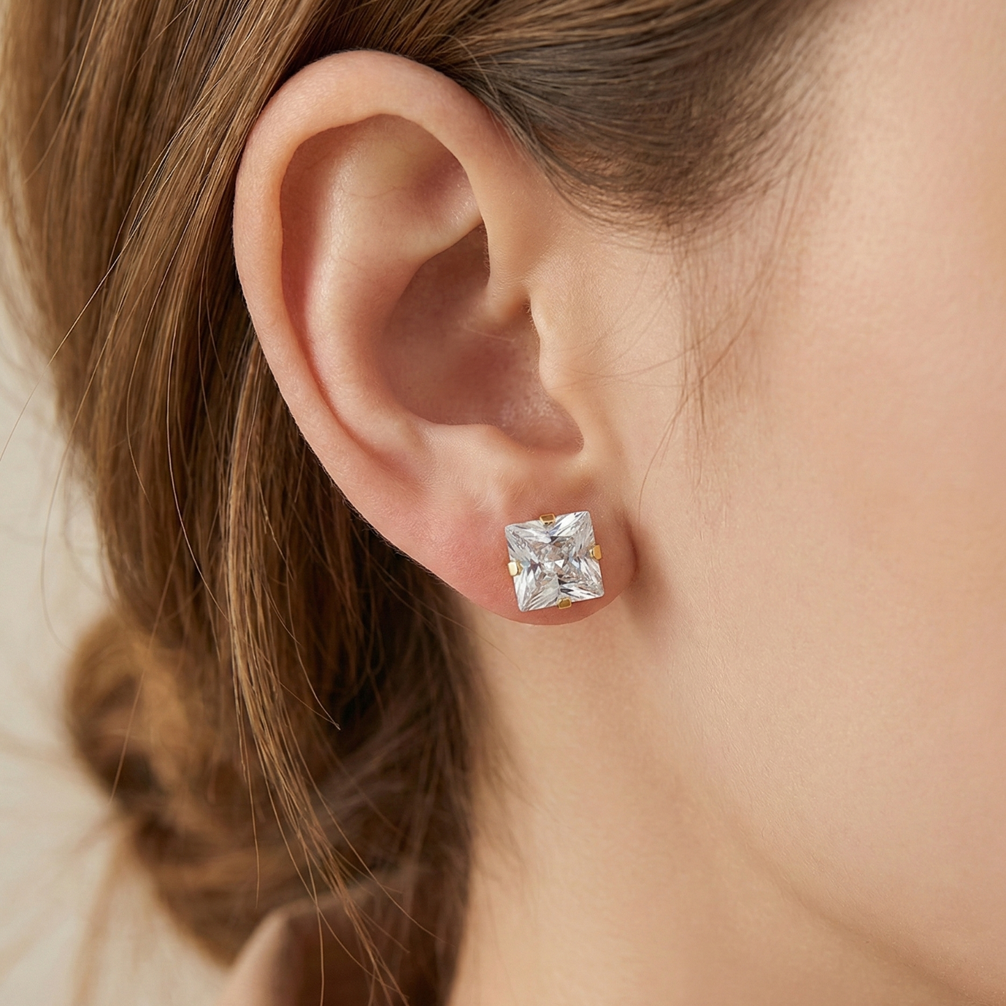 Close-up of an ear wearing a diamond earring with a blurred background