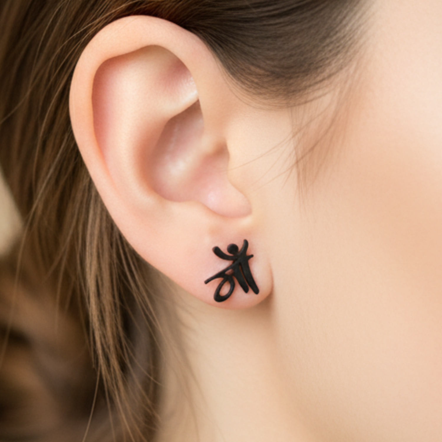 Close-up of an ear with a black insect-shaped earring on a blurred background