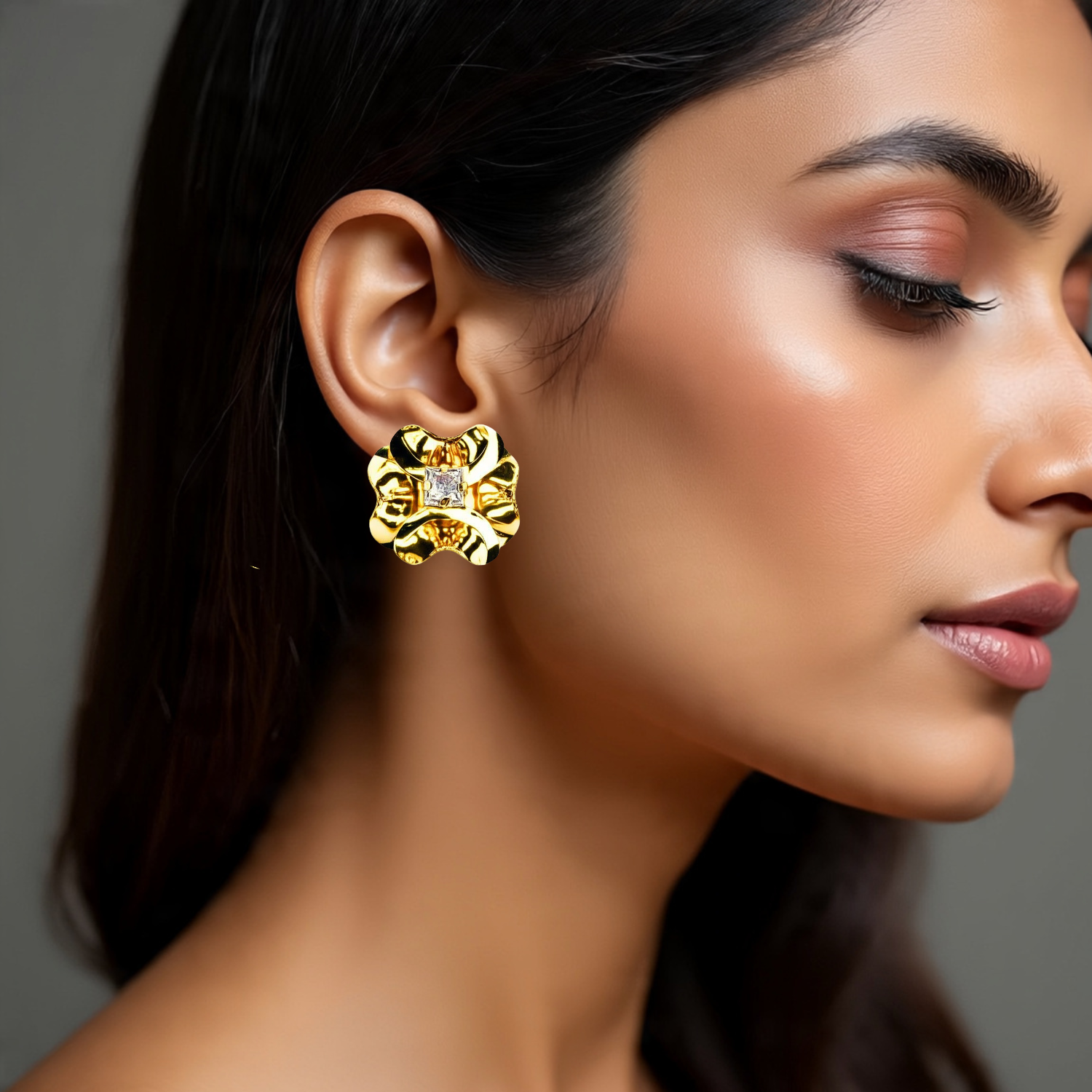 Close-up of a woman wearing gold earrings with a gray background