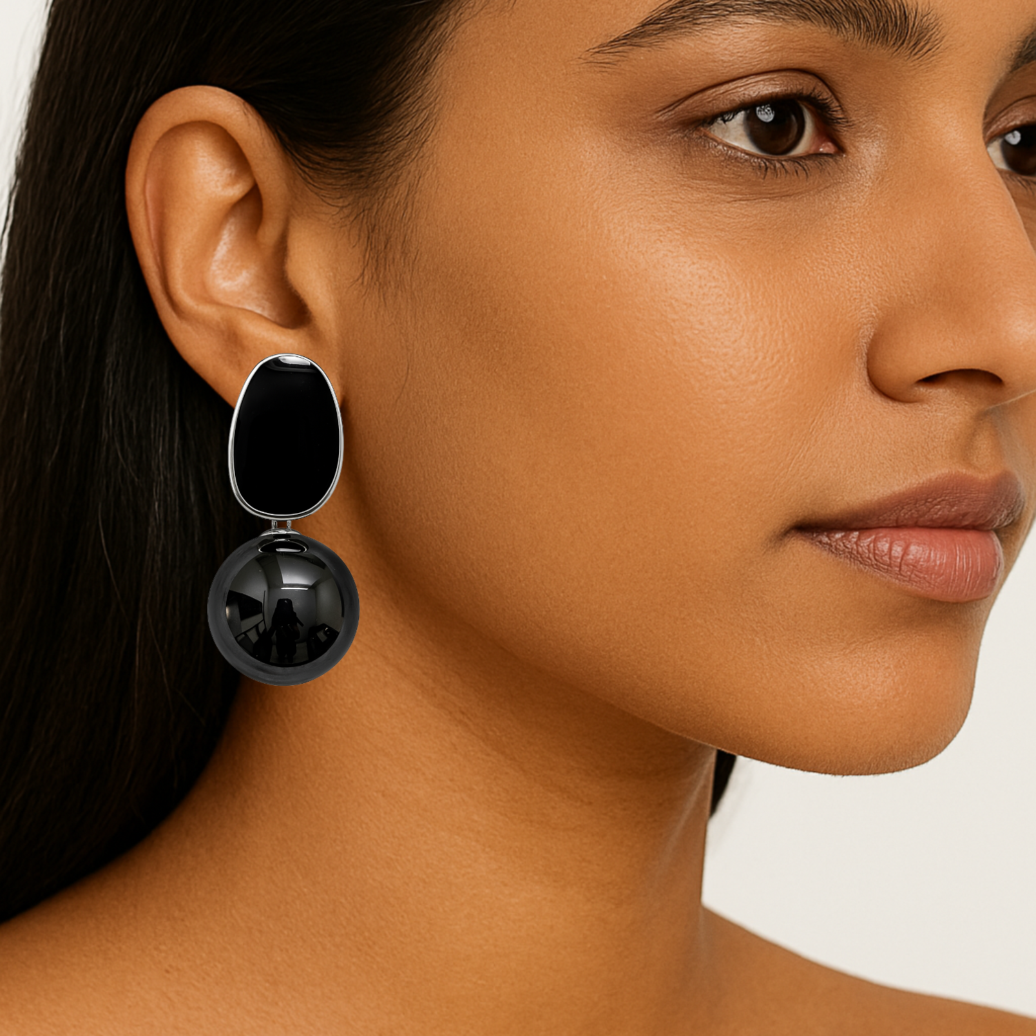 Close-up of a woman wearing black earrings with a neutral background