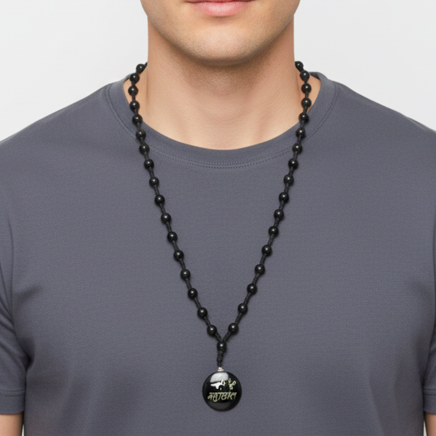 Man wearing a black beaded necklace with a pendant on a plain background