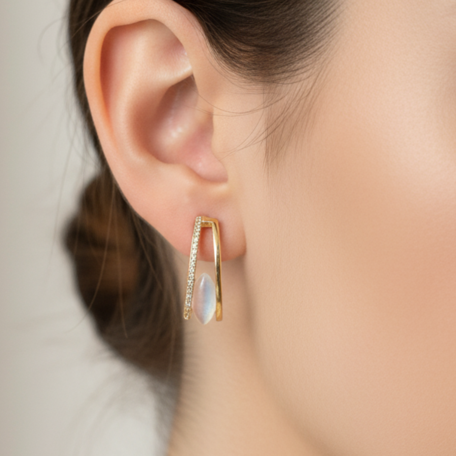 Gold earring with a gemstone worn by a person