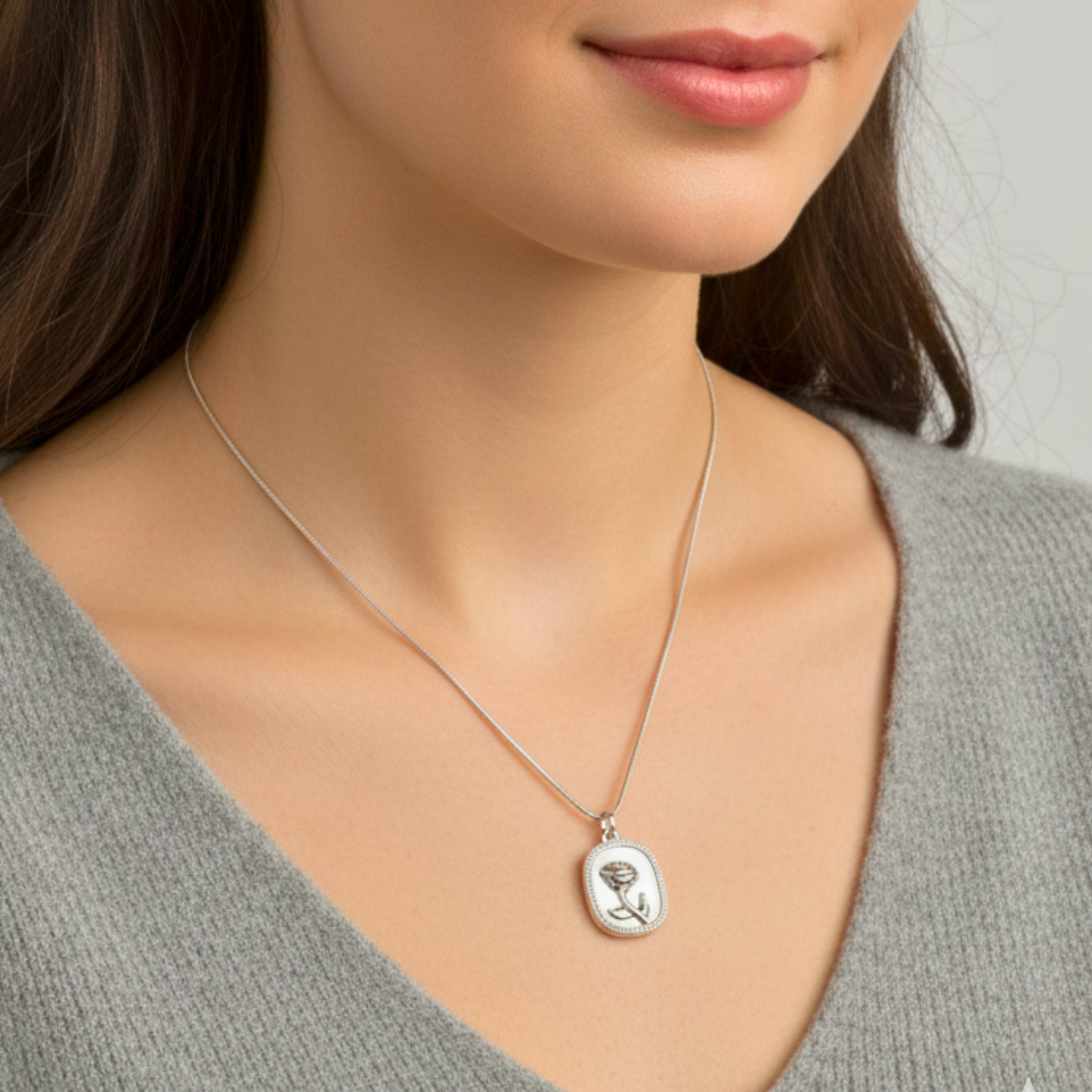 Close-up of a woman wearing a silver necklace with a pendant.