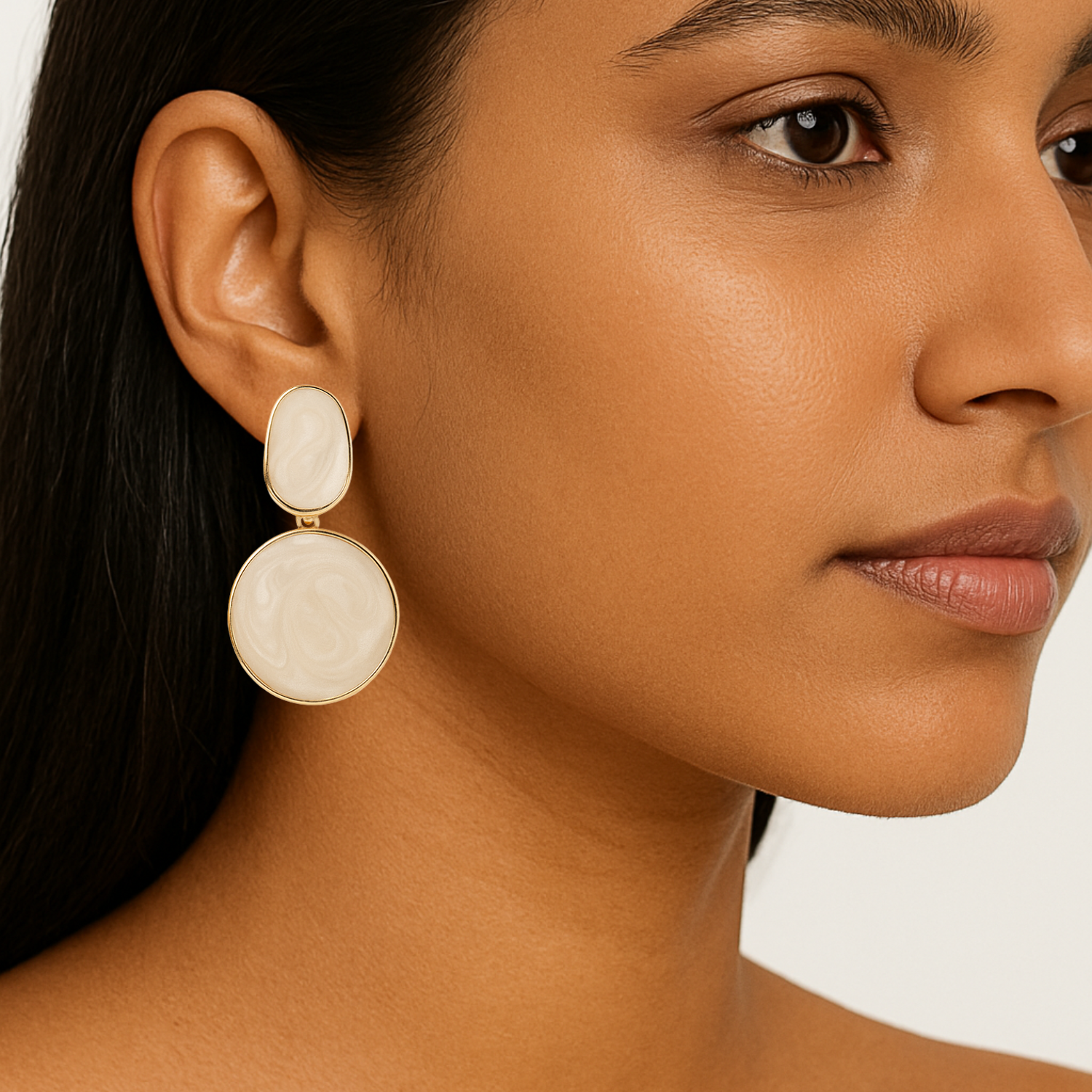 Close-up of a woman wearing beige earrings with a neutral background