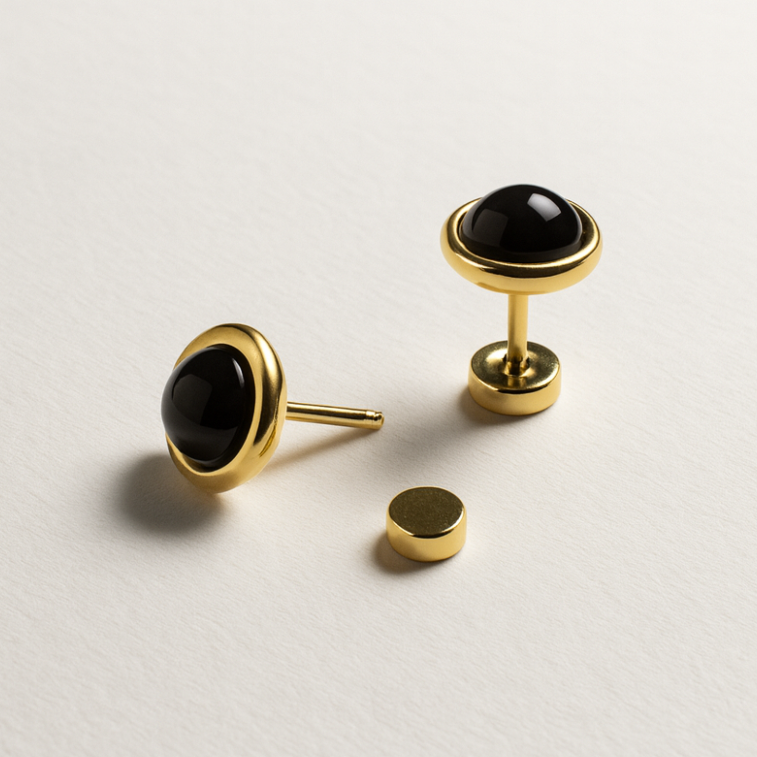Gold cufflinks with black stones on a light gray background