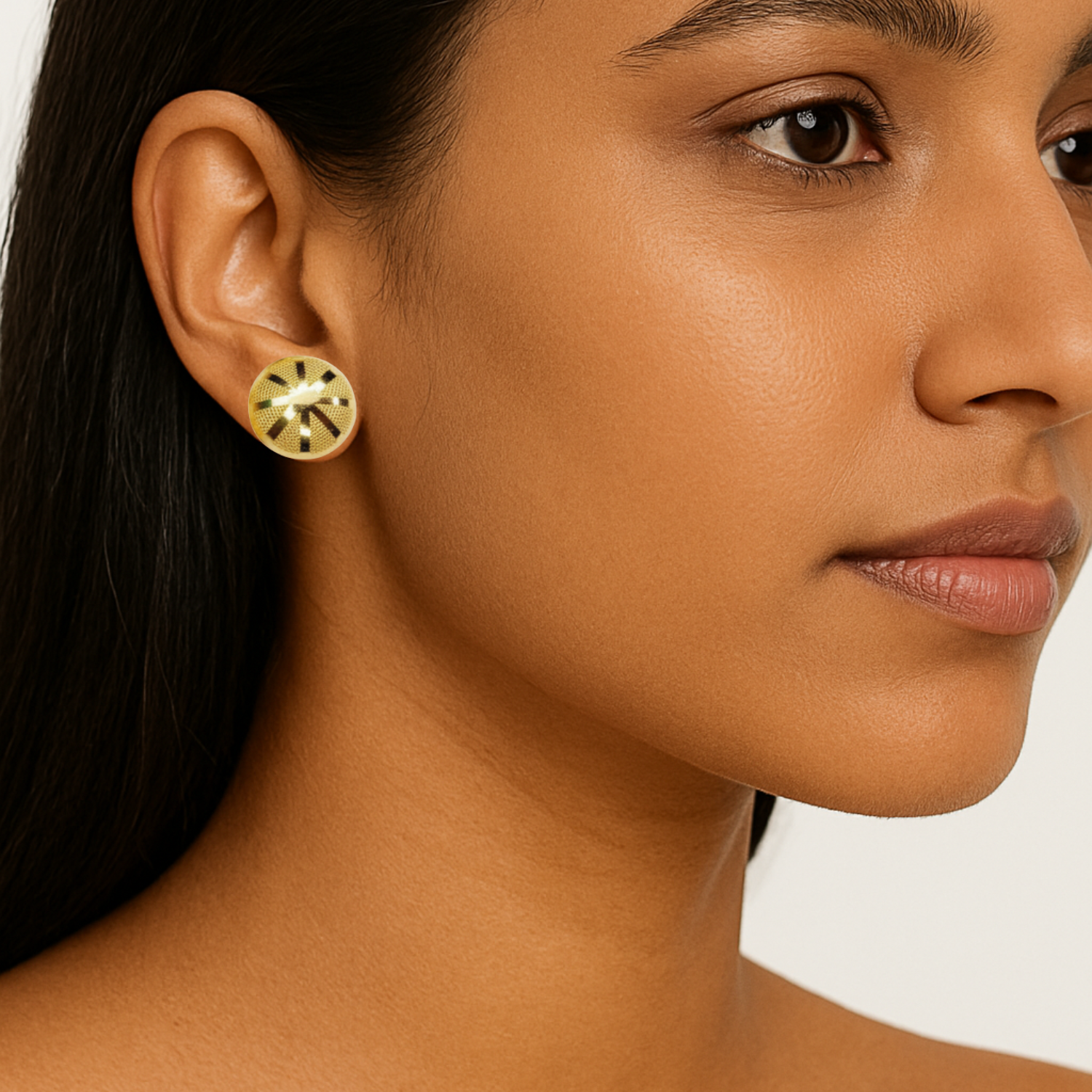 Close-up of a woman wearing gold earrings with a neutral background