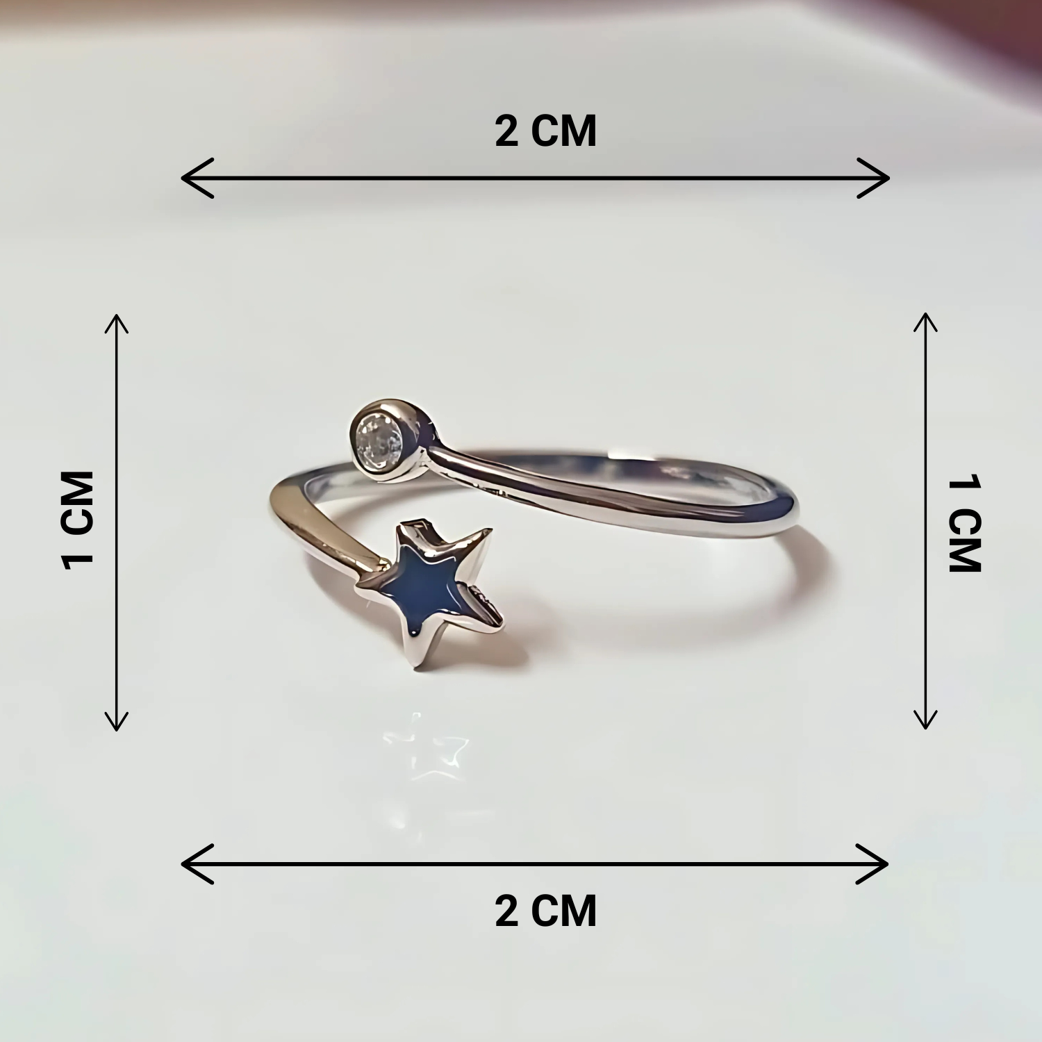 Silver ring with a black star charm and measurements on a white background