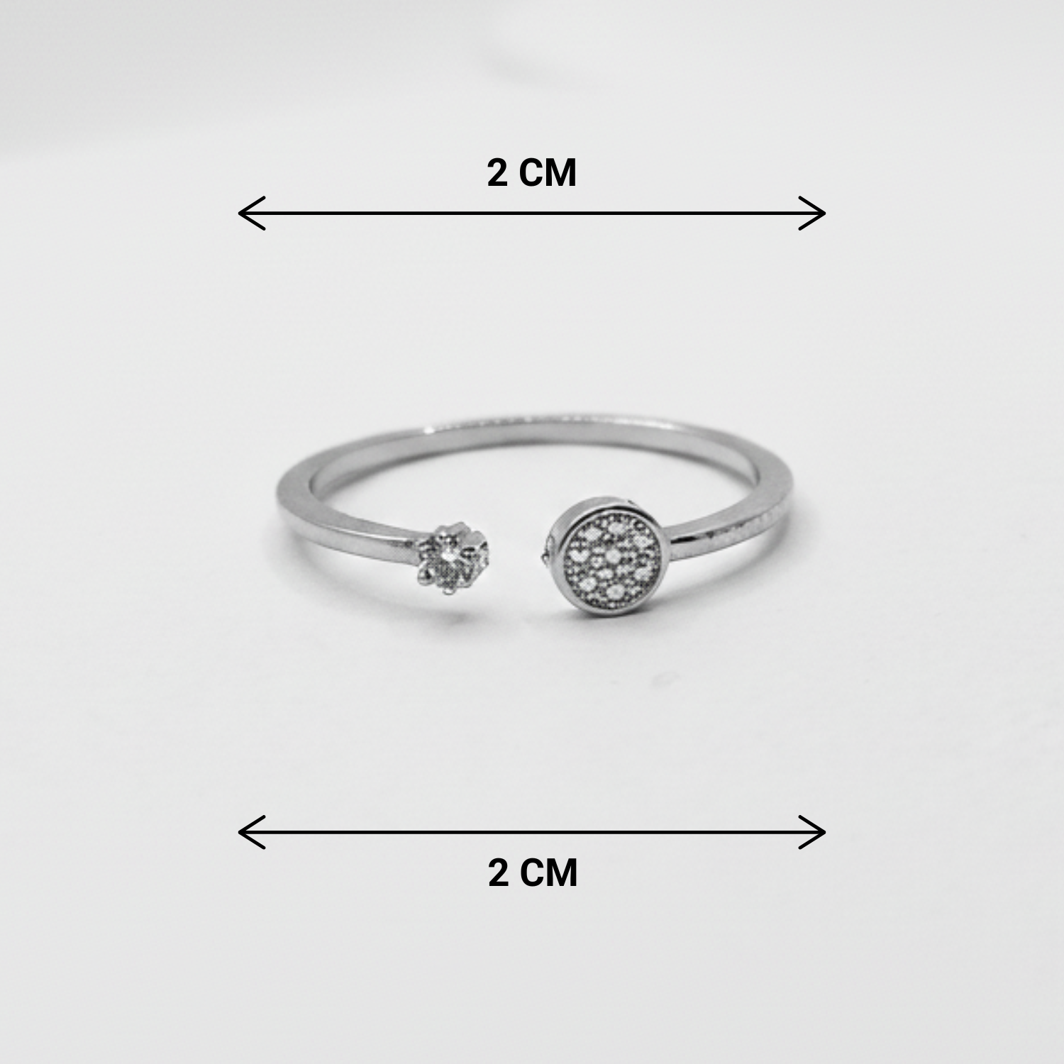 Silver ring with gemstones and measurement markings on a white background