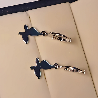 Pair of silver and silver earrings on a beige surface