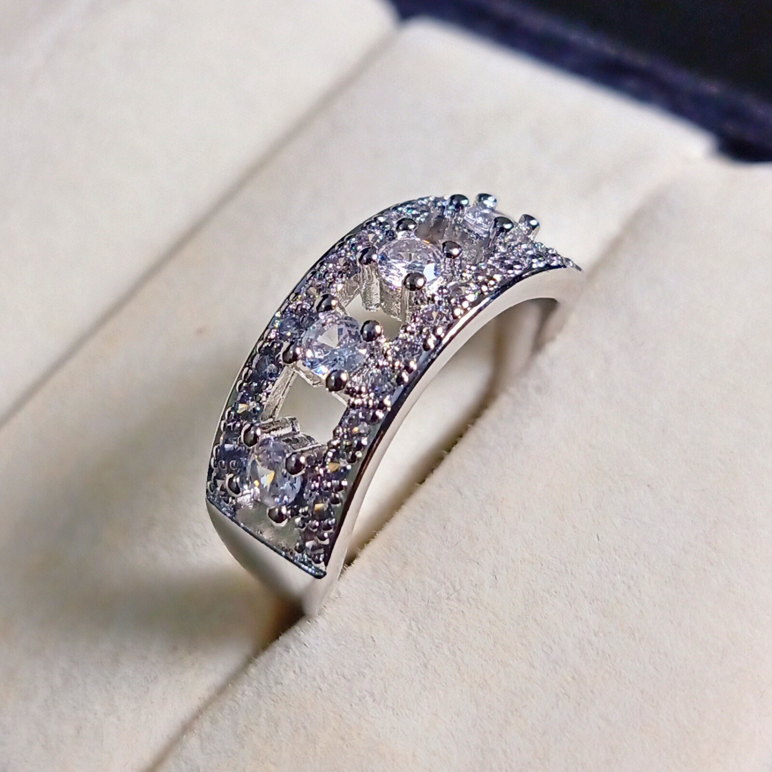 Silver ring with embedded stones on a soft beige background