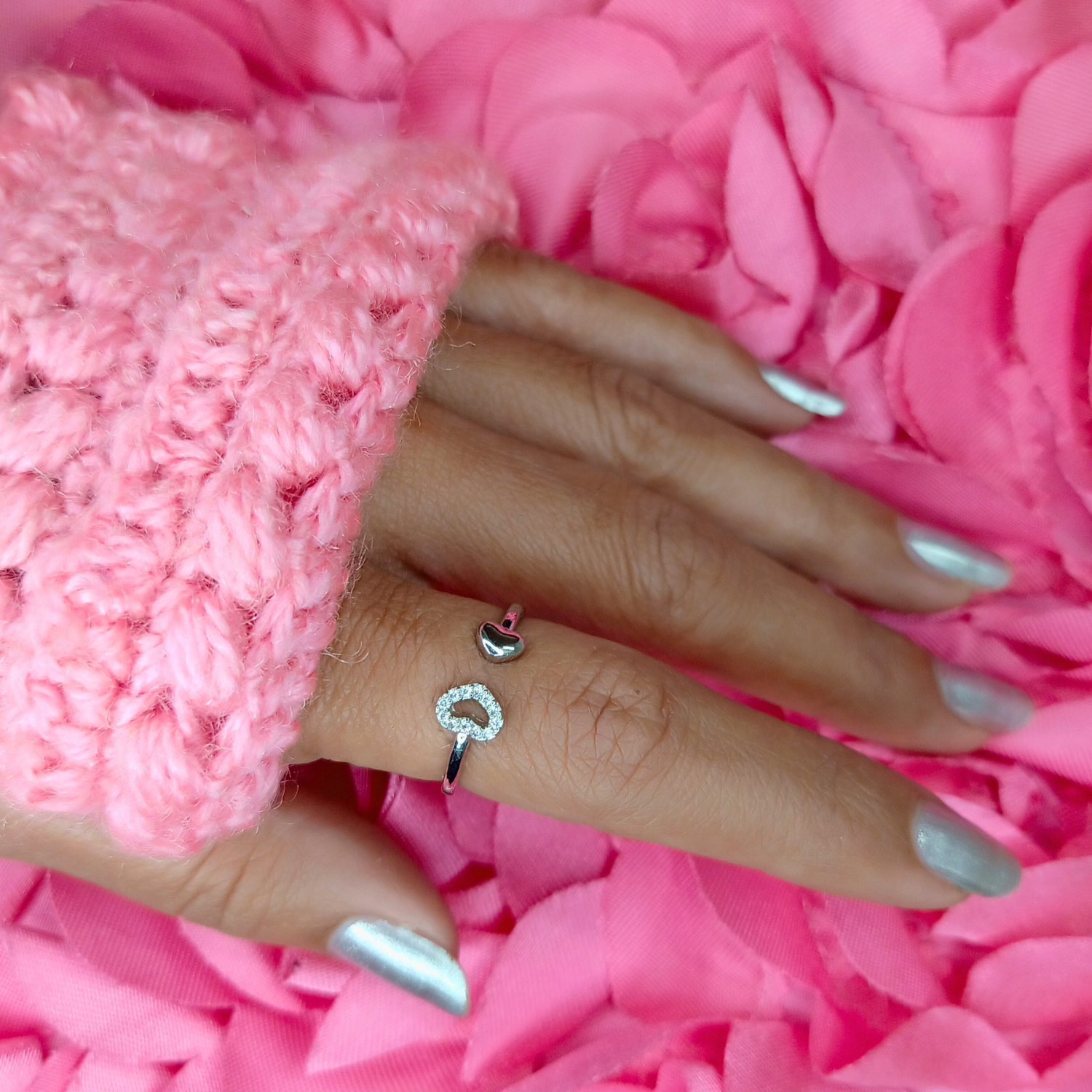Hand wearing a silver ring with a pink fluffy background