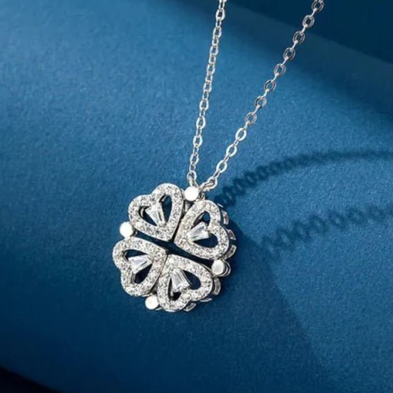 Silver necklace with a clover-shaped pendant on a blue background