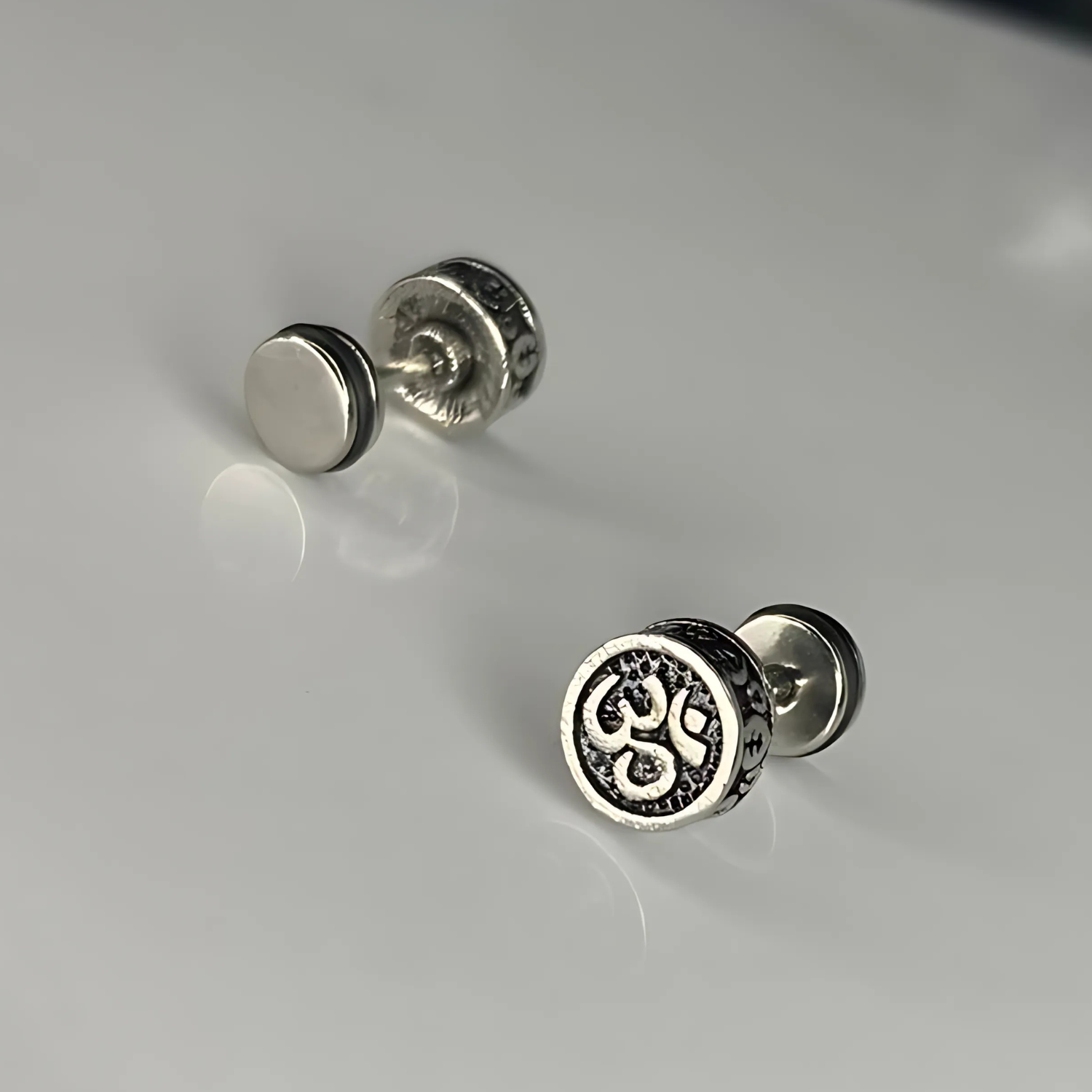 Pair of silver stud earrings on a light gray background