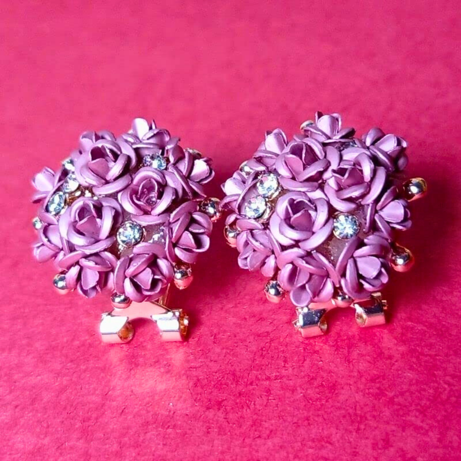 Pair of pink floral earrings with rhinestones on a pink background