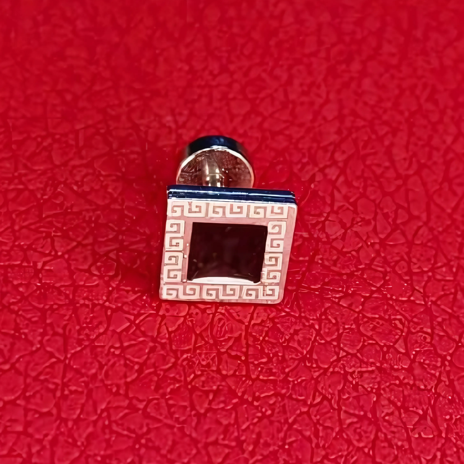 Cufflinks with a geometric design on a red textured background