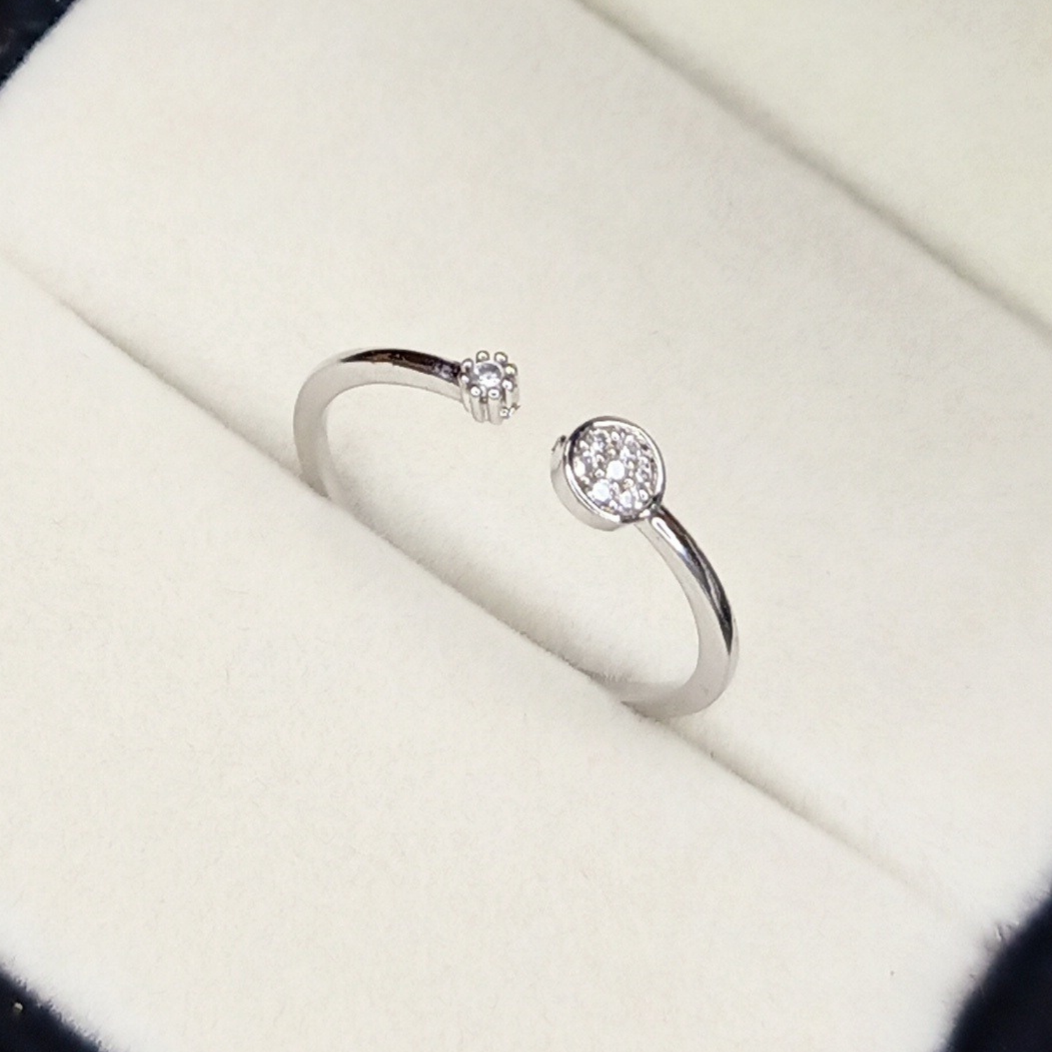 Silver open ring with gemstones on a white surface