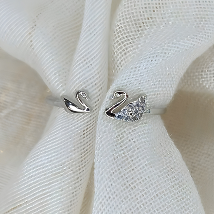 Silver swan-shaped earrings on a white fabric background