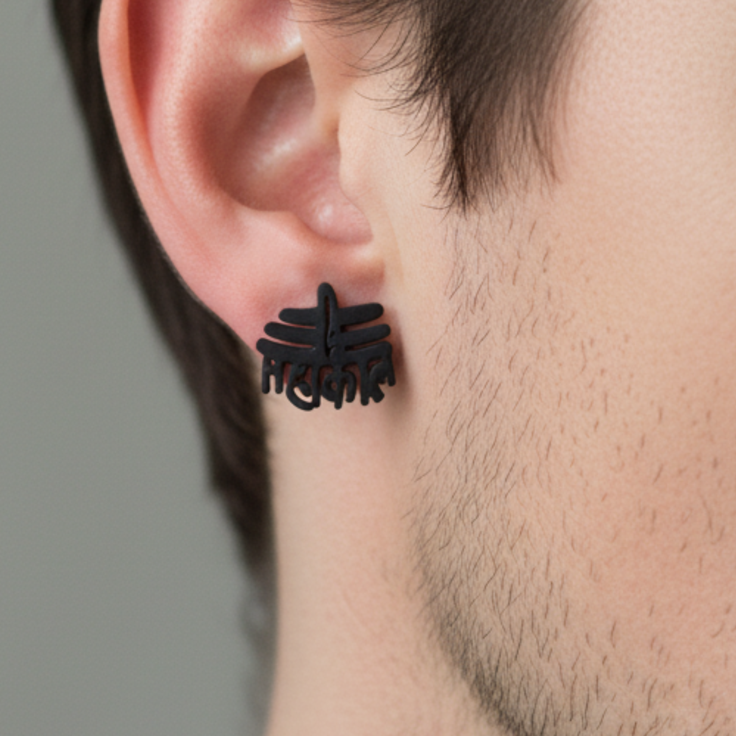 Black floral earring worn by a person with a neutral background