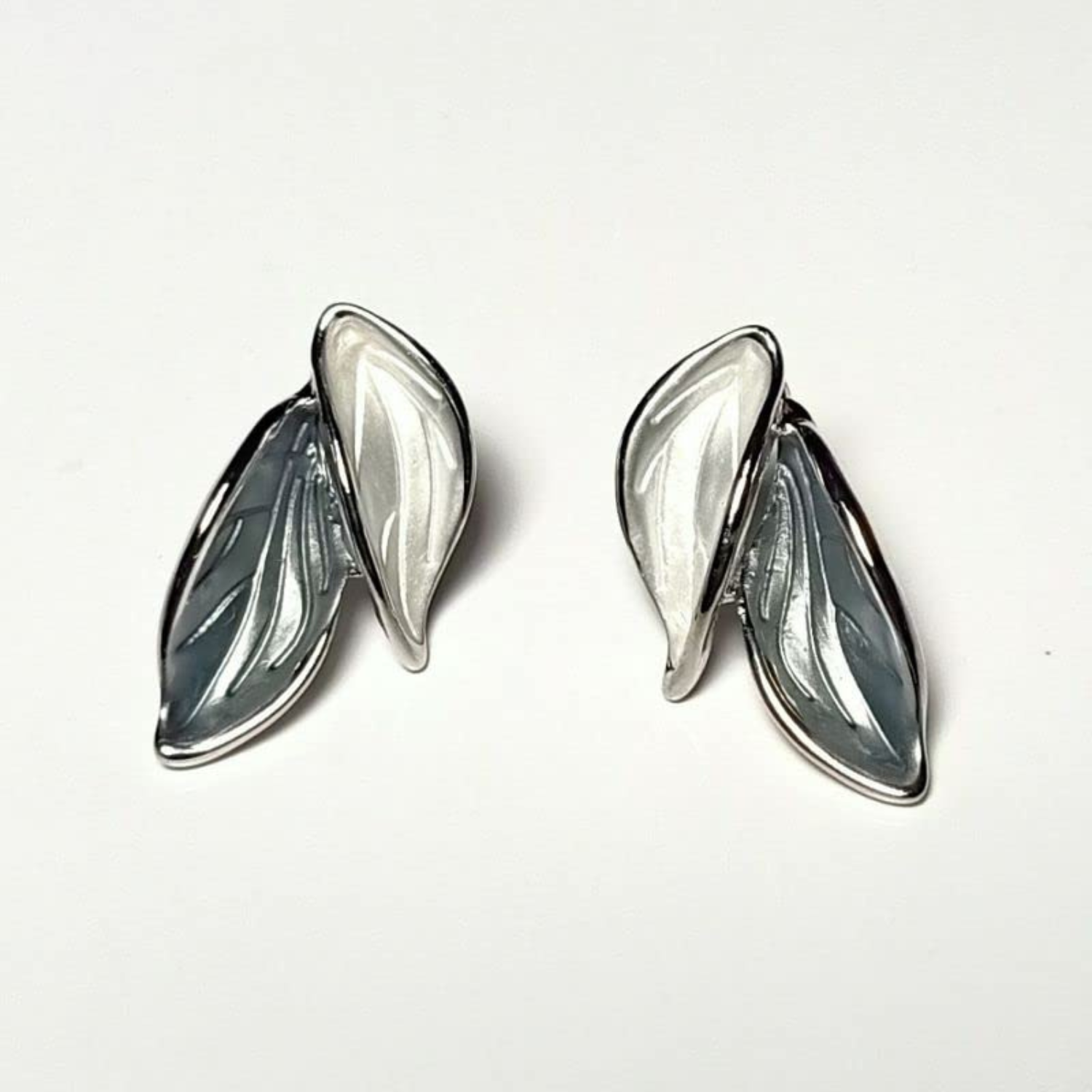 Pair of silver leaf-shaped earrings on a white background