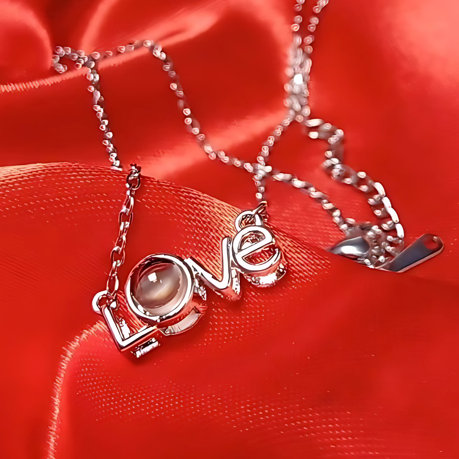Silver necklace with 'LOVE' pendant on a red fabric background