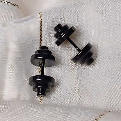 Black dumbbell-shaped earrings on a white textured background