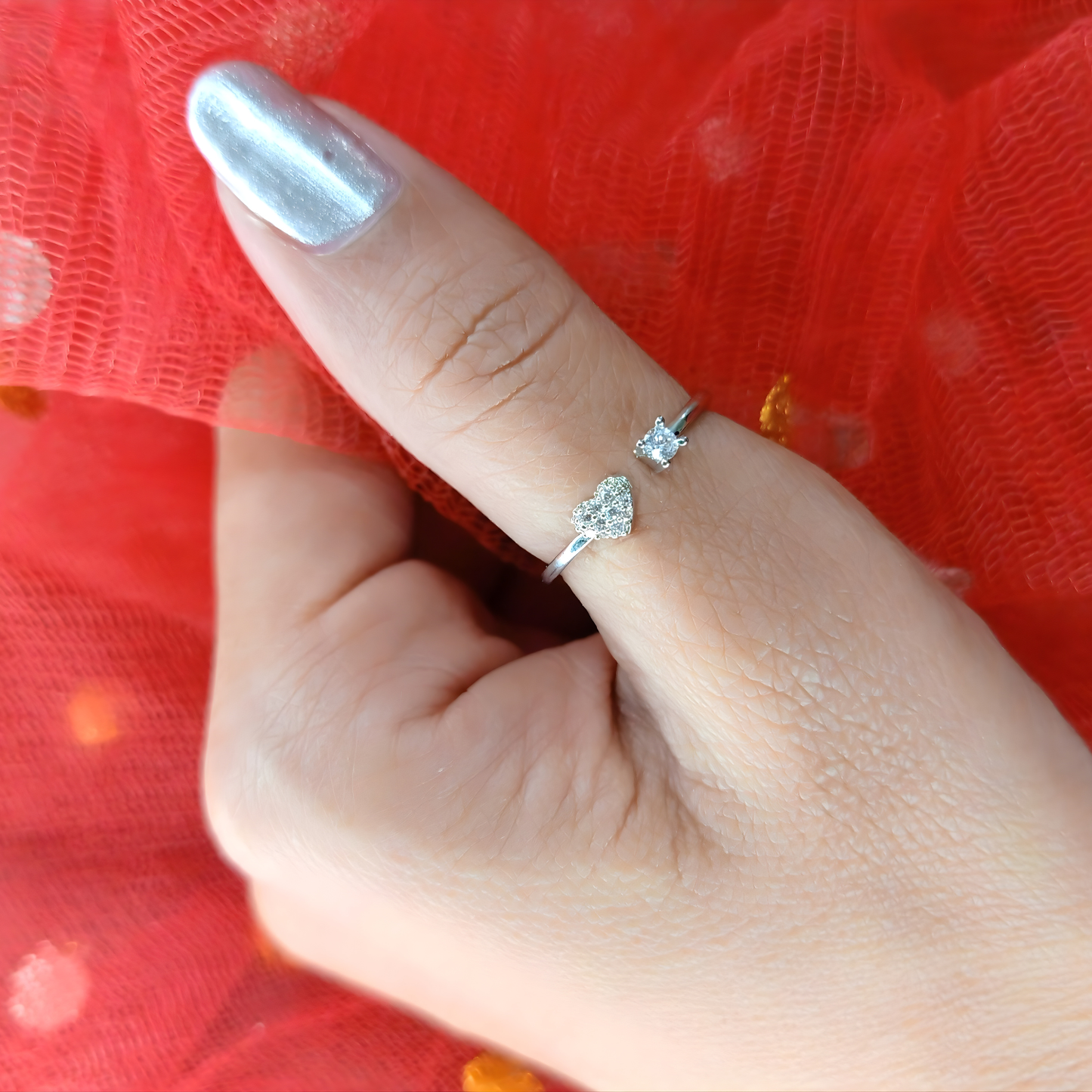 Hand wearing two diamond rings on a red fabric background