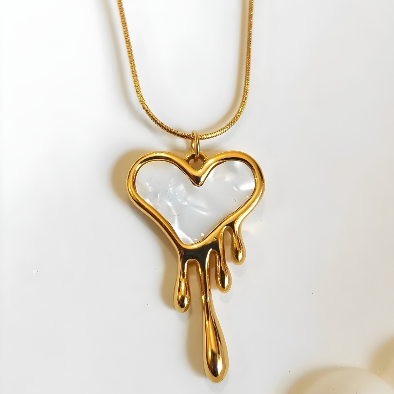 Gold heart-shaped pendant with a white center on a light background