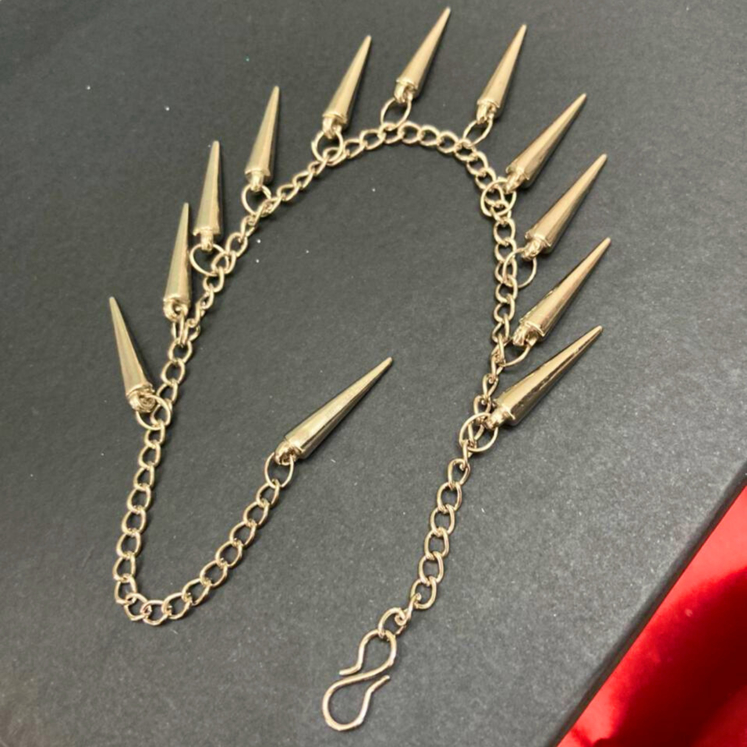 Silver chain earring with spike attachments on a dark background