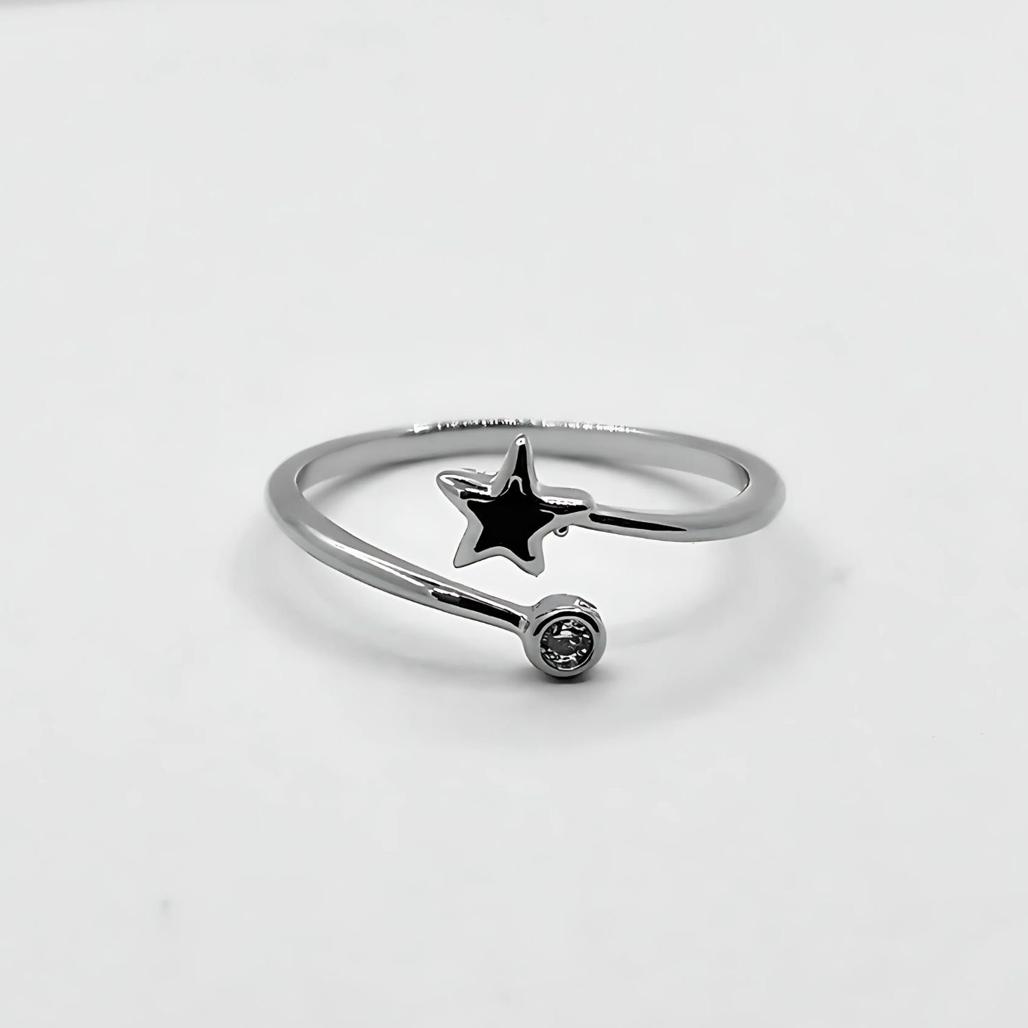 Silver ring with a star-shaped pendant on a light gray background