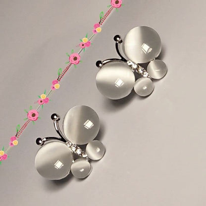 Butterfly-shaped jewelry with floral elements on a gray background