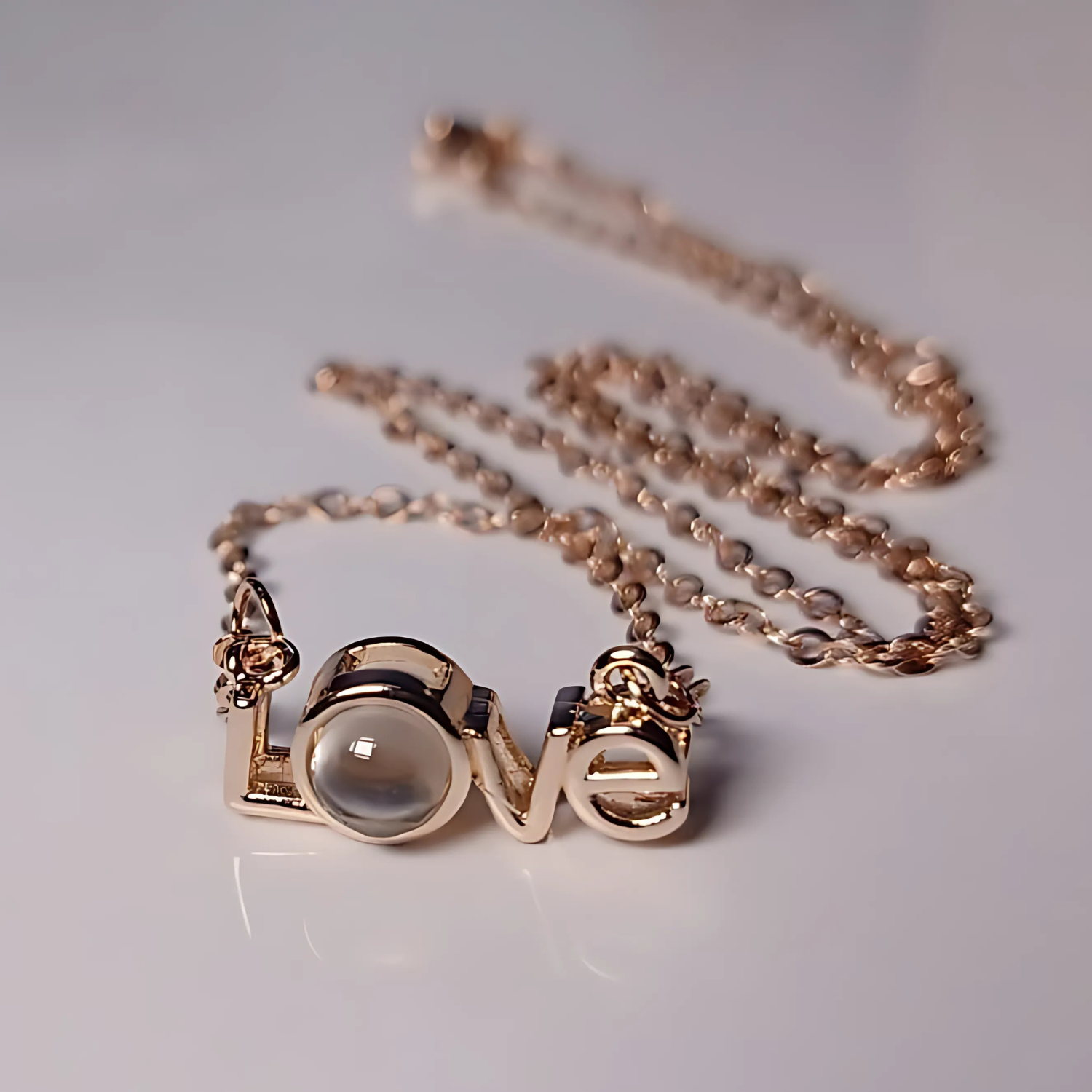 Rose gold necklace with 'love' pendant on a light gray background
