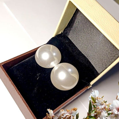 Pearl earrings in a jewelry box with flowers in the background