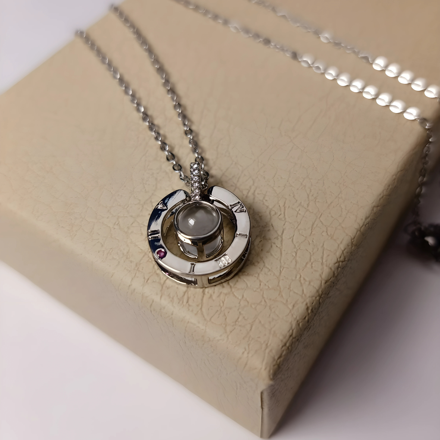 Silver necklace with a pendant on a beige box