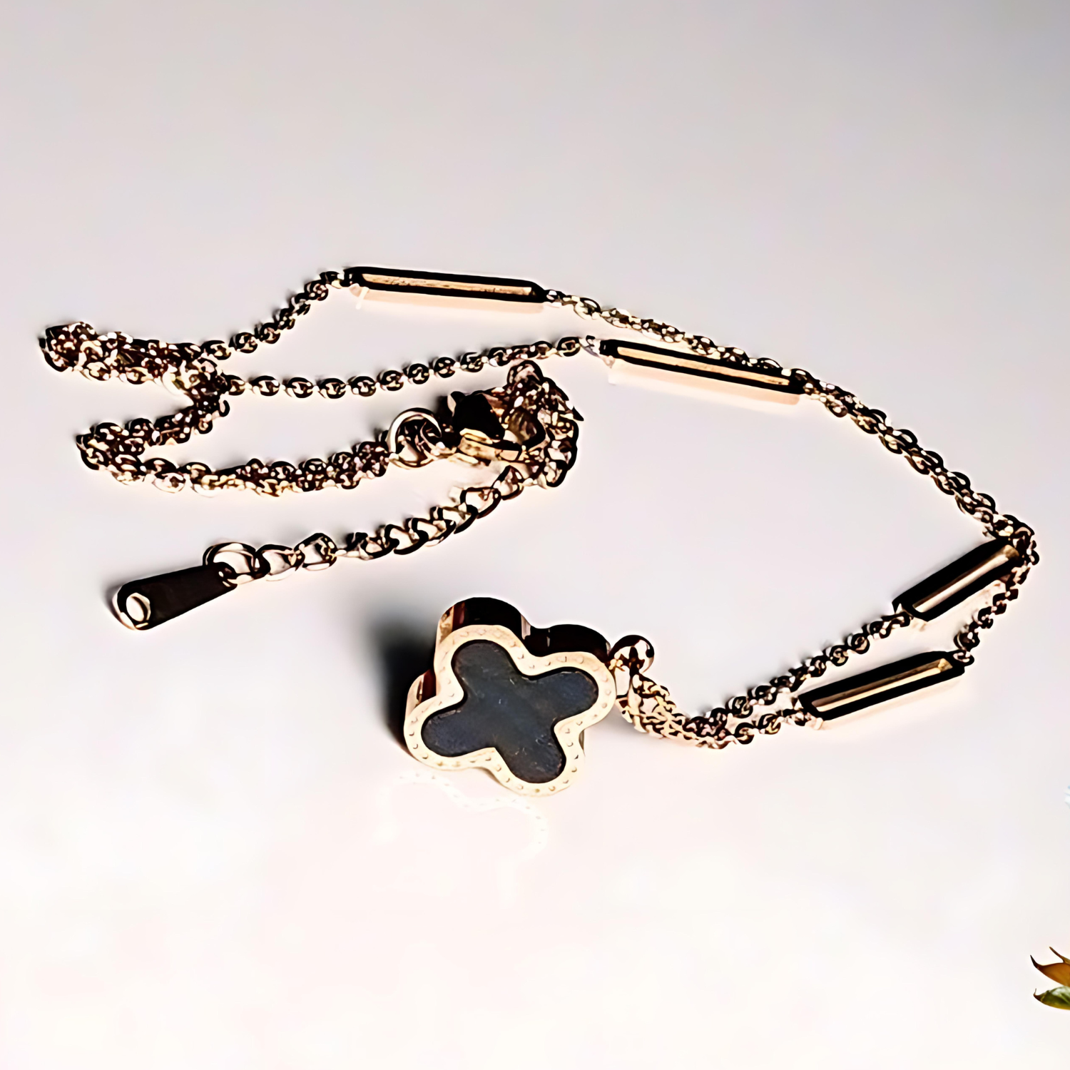 Gold chain with a clover-shaped pendant on a white background