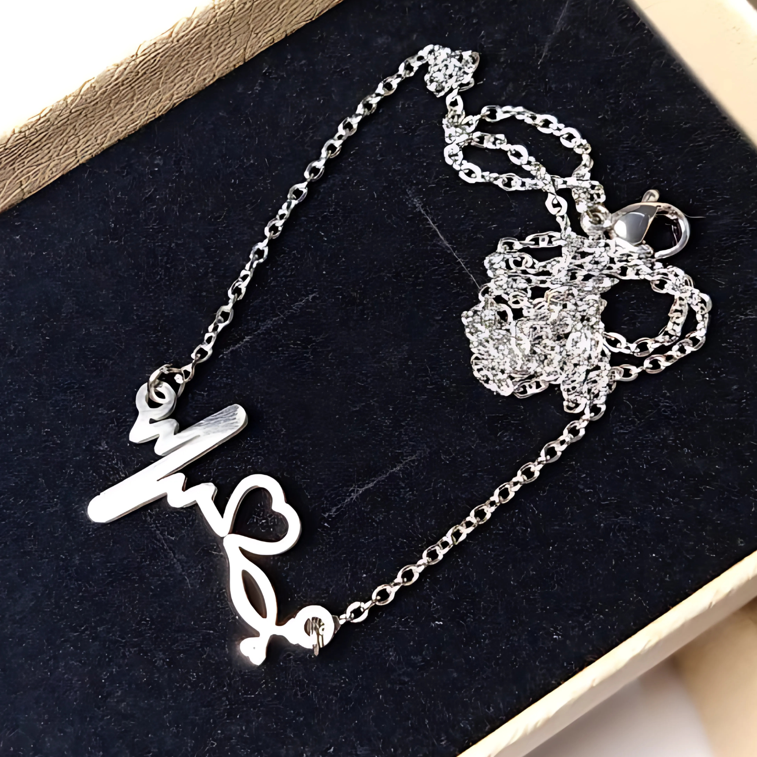 Silver necklace with heartbeat pendant on a black velvet surface
