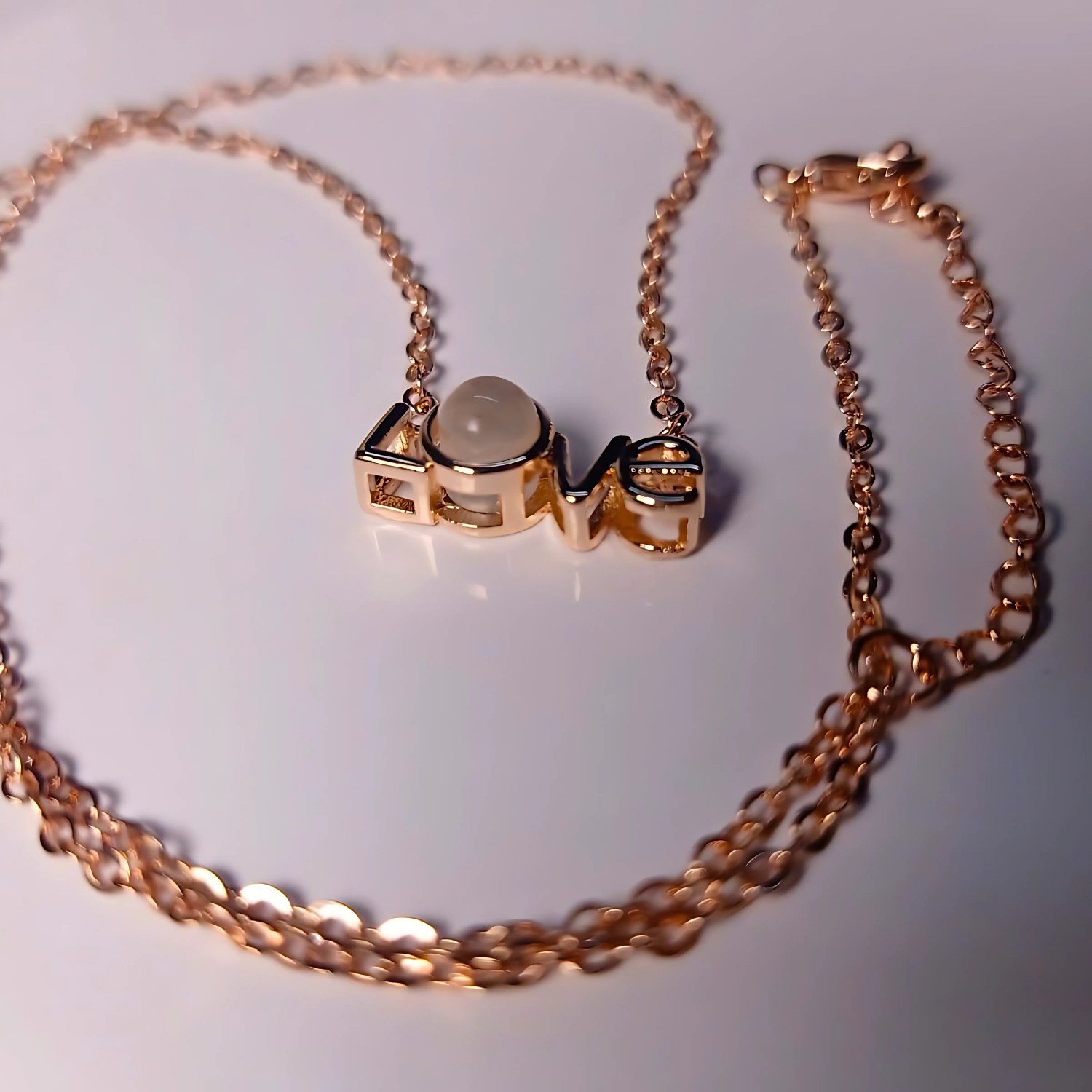 Rose gold necklace with a central pendant on a white background