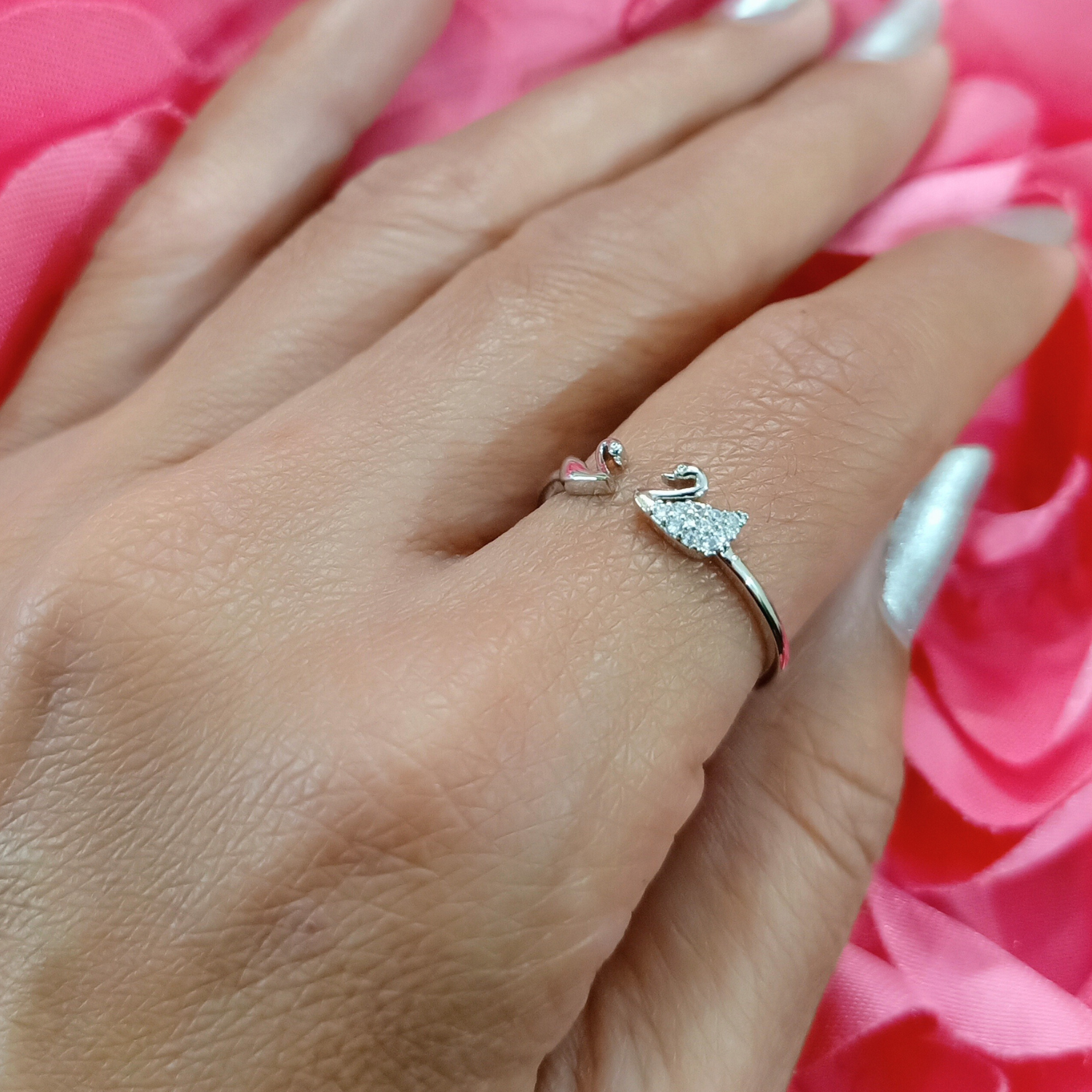 Hand wearing two rings with a pink floral background