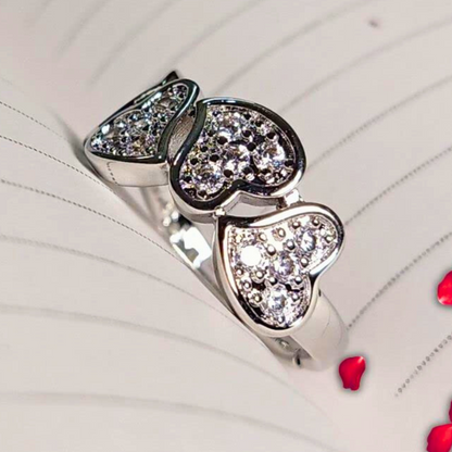 Silver ring with heart-shaped gemstones on a white background