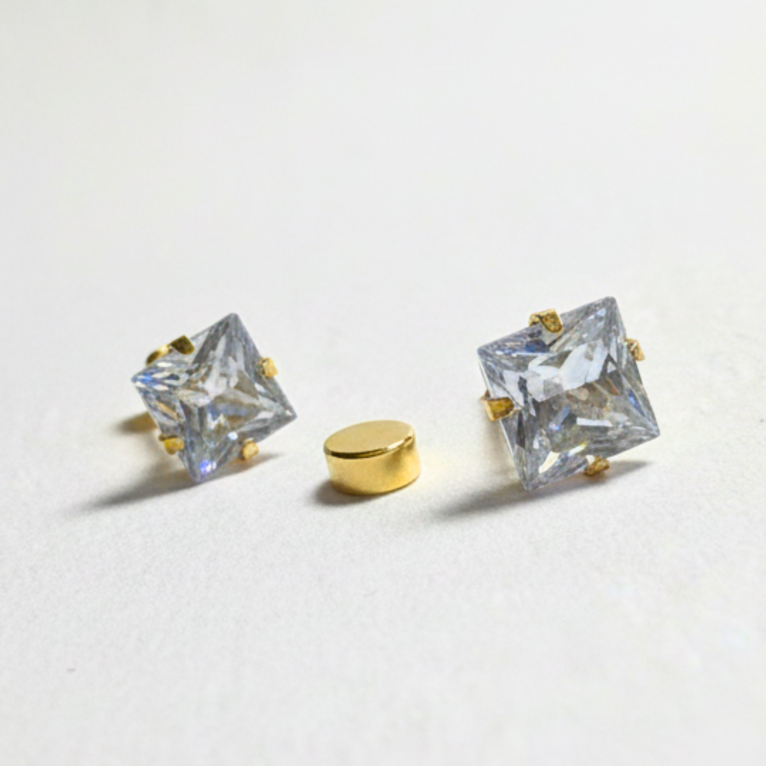 Gold earrings with clear gemstones on a light gray background